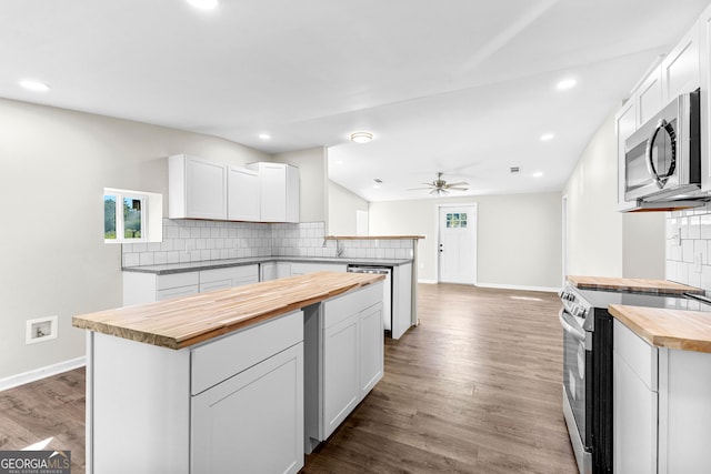 kitchen with tasteful backsplash, dark wood finished floors, a peninsula, stainless steel appliances, and wooden counters