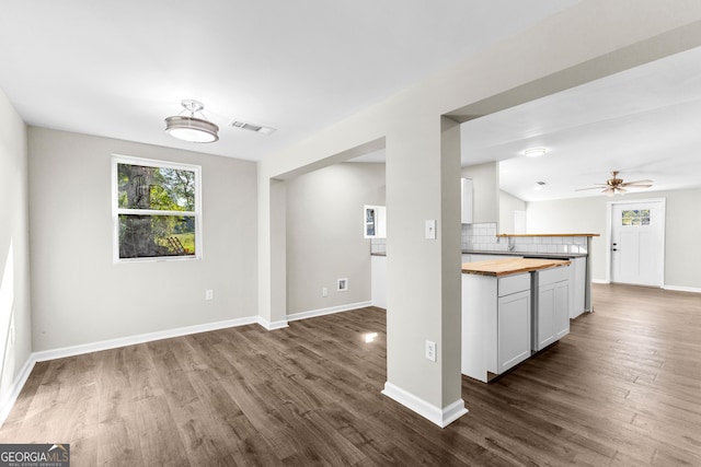 kitchen featuring butcher block countertops, dark wood-style flooring, visible vents, and decorative backsplash