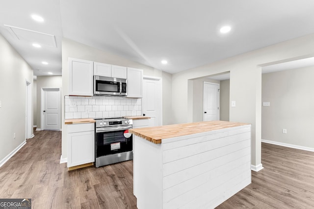 kitchen featuring appliances with stainless steel finishes, decorative backsplash, wood counters, and white cabinets