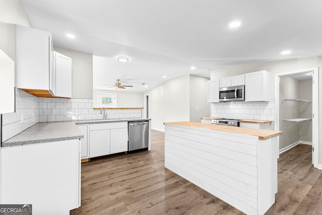 kitchen featuring appliances with stainless steel finishes, white cabinets, and light wood-style floors