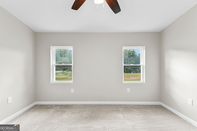 carpeted empty room with ceiling fan, plenty of natural light, and baseboards