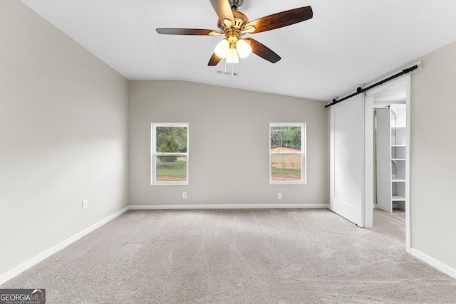 unfurnished bedroom featuring carpet floors, a barn door, multiple windows, and baseboards