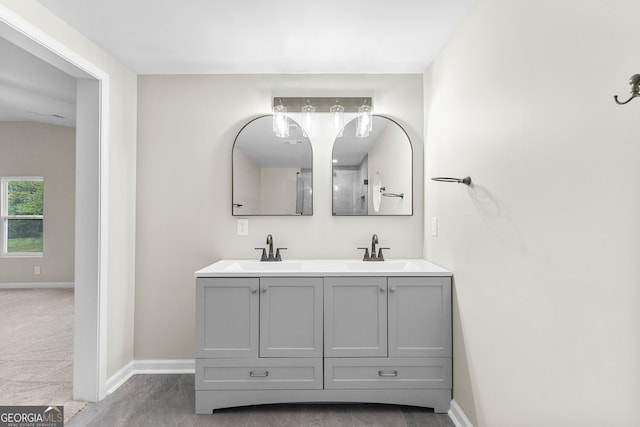 bathroom with double vanity, baseboards, and a sink