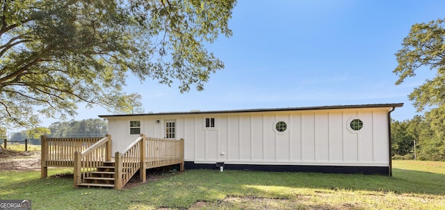 rear view of house featuring board and batten siding, crawl space, a wooden deck, and a lawn