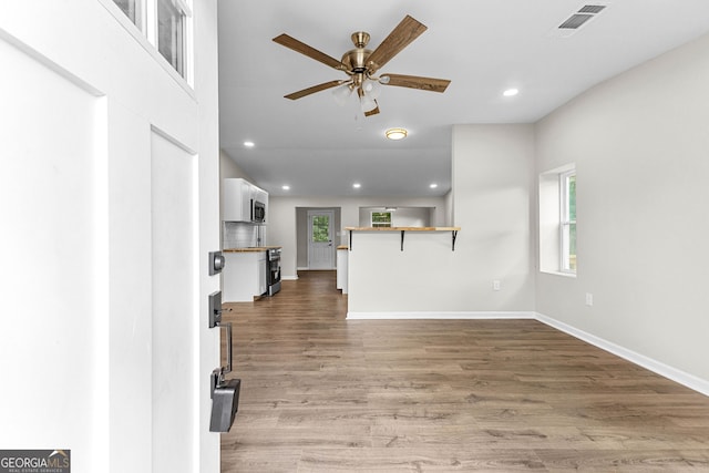 unfurnished living room with recessed lighting, wood finished floors, a ceiling fan, baseboards, and visible vents