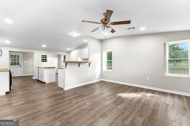 unfurnished living room with lofted ceiling, dark wood-type flooring, visible vents, and baseboards