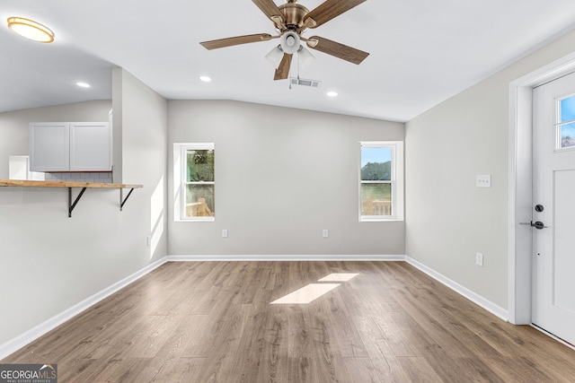 unfurnished living room with baseboards, visible vents, a wealth of natural light, and wood finished floors