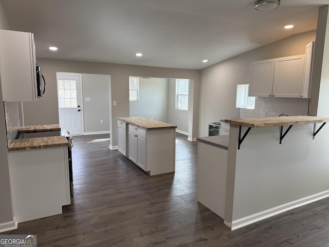 kitchen with butcher block counters, stainless steel microwave, and dark wood finished floors