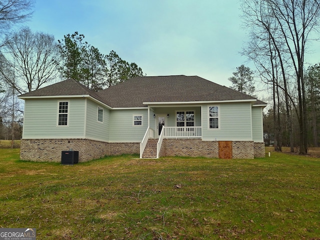 single story home featuring roof with shingles, a porch, cooling unit, and a front yard