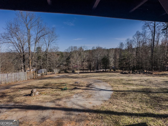 view of yard featuring fence and a wooded view