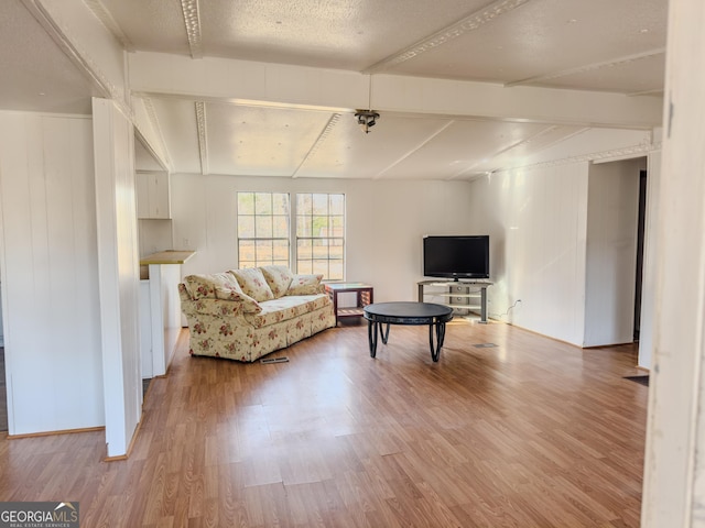 living area with light wood-type flooring, baseboards, and beam ceiling