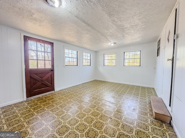 foyer entrance featuring a textured ceiling, baseboards, and tile patterned floors