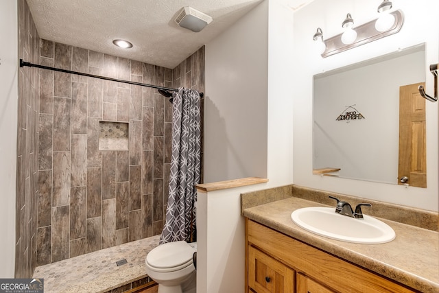 full bath with visible vents, toilet, a textured ceiling, vanity, and tiled shower