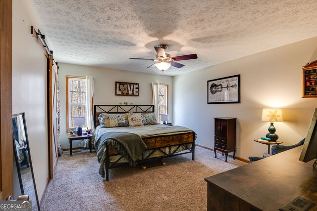 bedroom featuring a barn door, baseboards, a ceiling fan, and light colored carpet