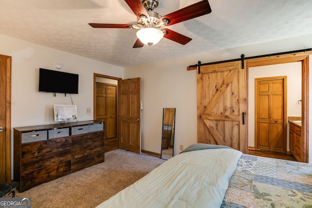 carpeted bedroom with baseboards, a barn door, a ceiling fan, and a textured ceiling