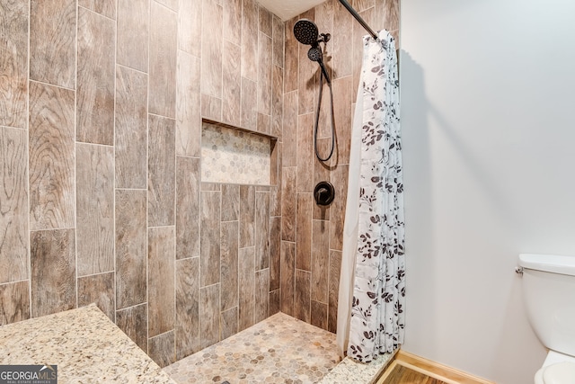 full bath with a tile shower and toilet