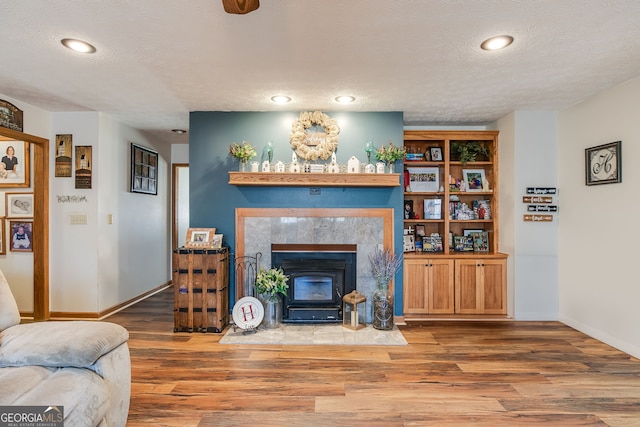 living area featuring a textured ceiling, recessed lighting, wood finished floors, and baseboards