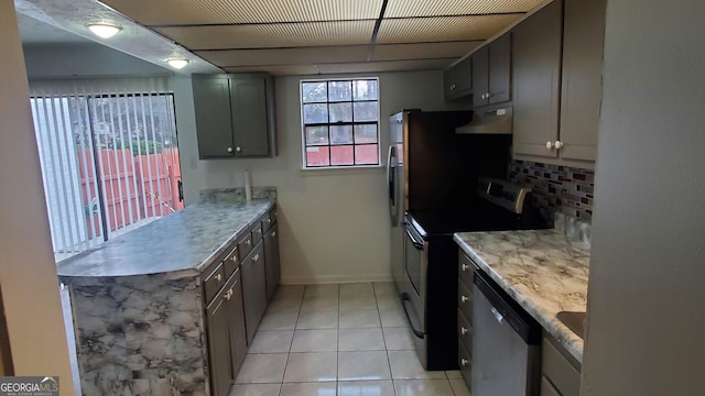 kitchen featuring light tile patterned floors, stainless steel appliances, tasteful backsplash, a peninsula, and under cabinet range hood