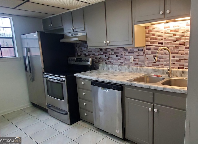 kitchen featuring appliances with stainless steel finishes, gray cabinets, a sink, and under cabinet range hood