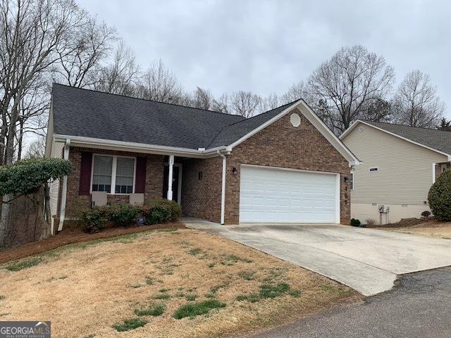 single story home with an attached garage, brick siding, driveway, and a shingled roof