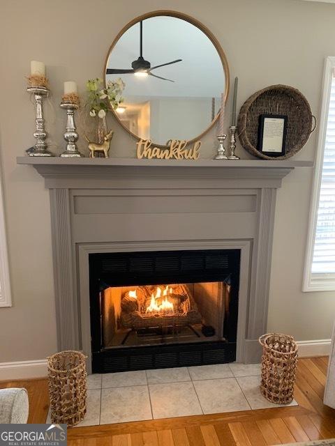 interior details with a fireplace with flush hearth, baseboards, and wood finished floors