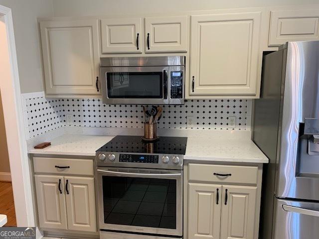 kitchen with decorative backsplash, stainless steel appliances, and light stone countertops