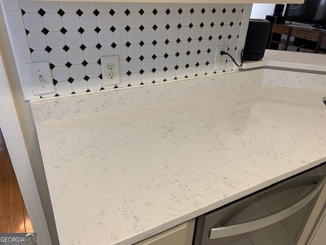 room details featuring light stone counters and stainless steel dishwasher