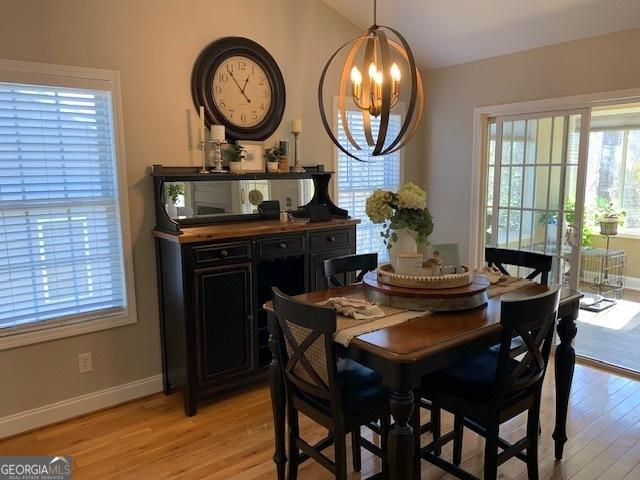 dining space with light wood-style flooring, baseboards, and an inviting chandelier