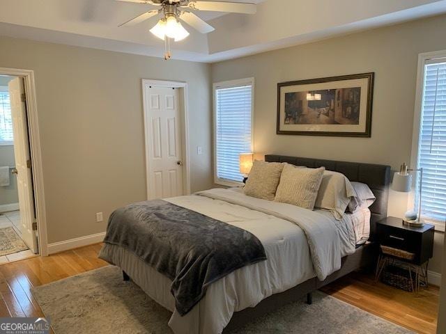 bedroom with multiple windows, baseboards, light wood finished floors, and ceiling fan