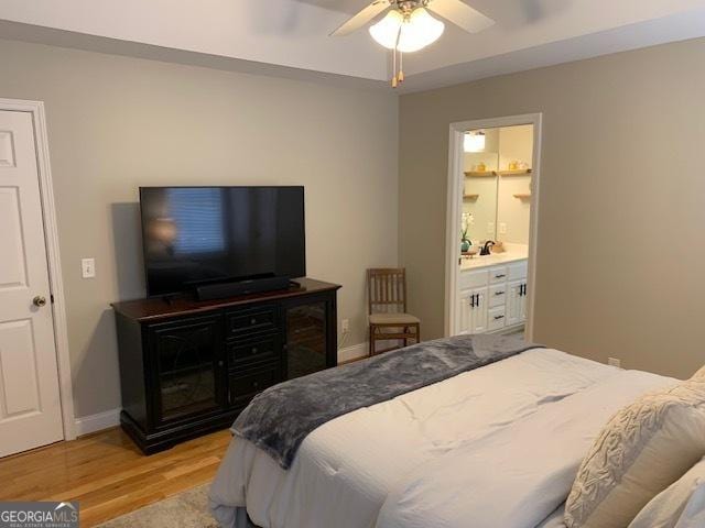 bedroom with light wood-type flooring, ensuite bathroom, baseboards, and a ceiling fan