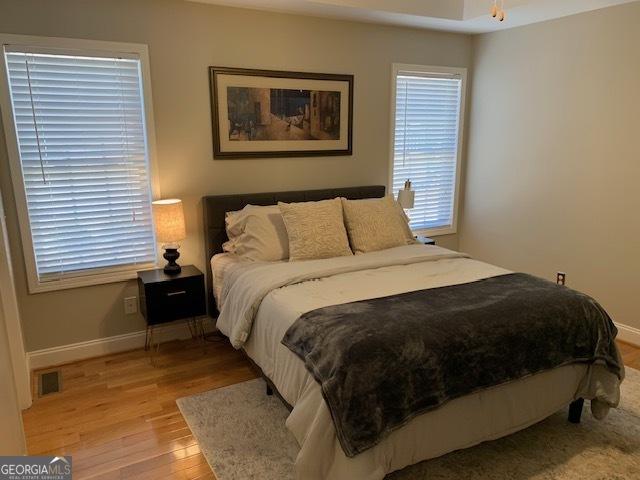 bedroom featuring light wood-style flooring, visible vents, and baseboards