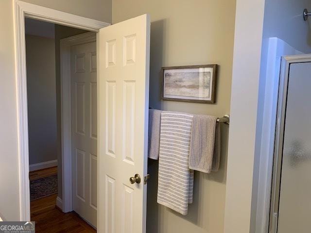 bathroom with a shower with door, baseboards, and wood finished floors