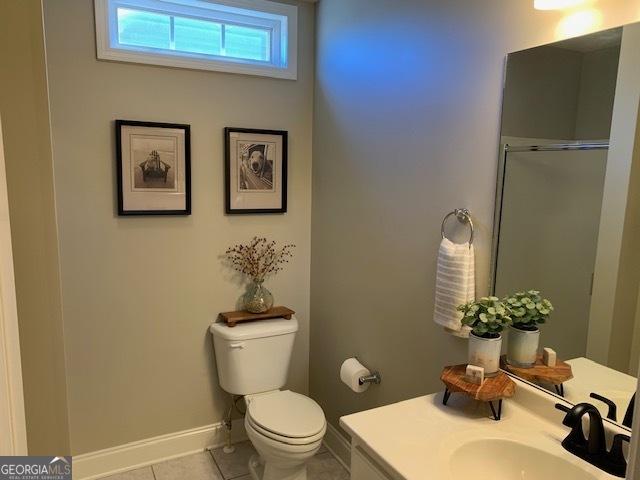 full bathroom featuring a shower with door, baseboards, toilet, tile patterned floors, and vanity