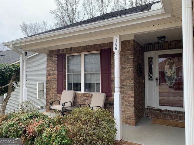 doorway to property with brick siding and covered porch