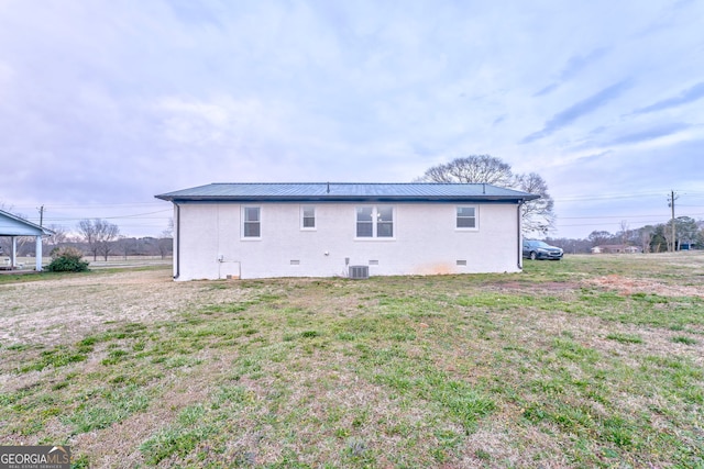 back of house with crawl space, central air condition unit, a yard, and metal roof