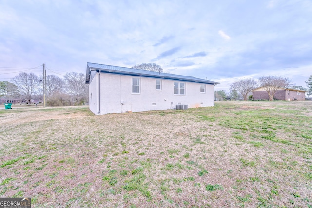 back of property featuring metal roof, a yard, central AC unit, and crawl space