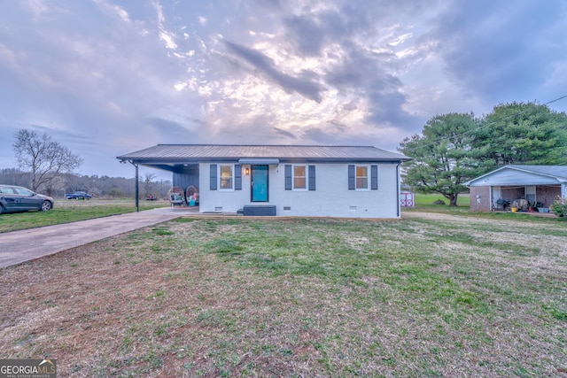 ranch-style house with an attached carport, concrete driveway, metal roof, and a front yard