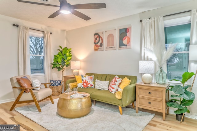 living area with baseboards, wood finished floors, and a ceiling fan