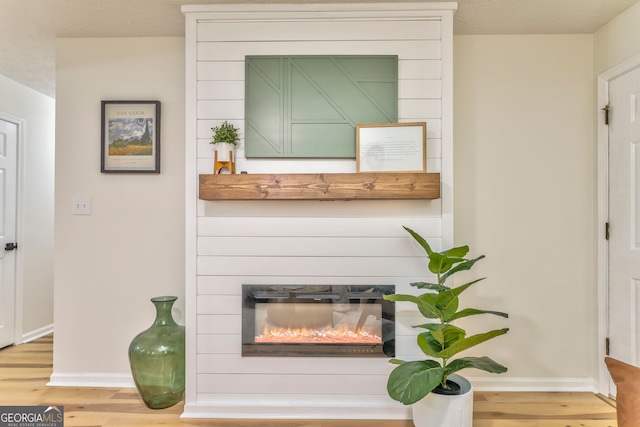 interior details featuring baseboards, a large fireplace, and wood finished floors