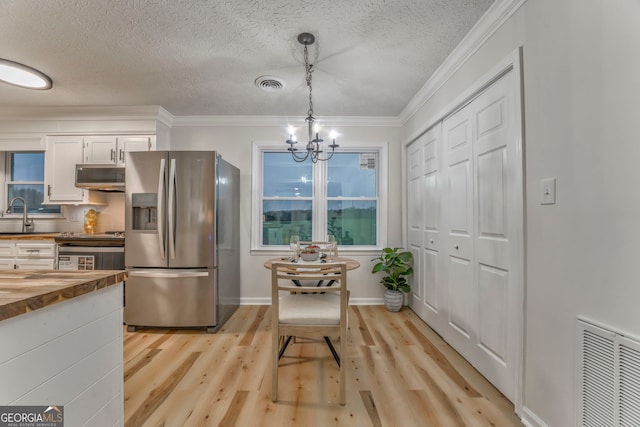 kitchen featuring visible vents, wooden counters, a sink, appliances with stainless steel finishes, and pendant lighting