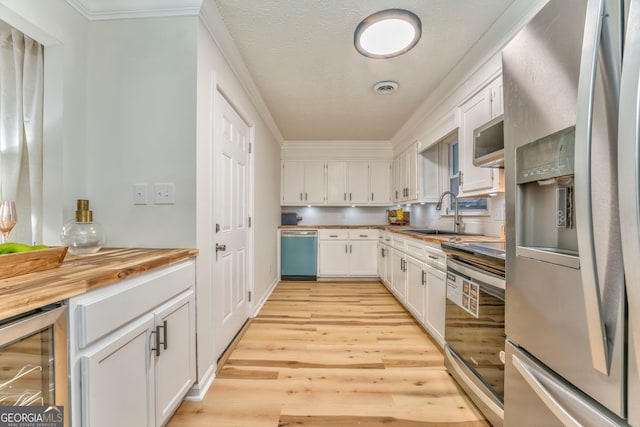 kitchen with white cabinetry, wine cooler, light wood-style flooring, and stainless steel appliances