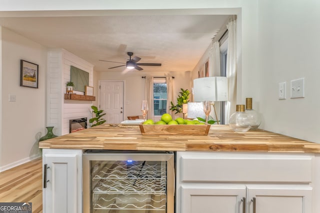 kitchen featuring light wood finished floors, wine cooler, butcher block counters, white cabinetry, and a ceiling fan