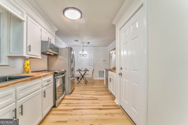 kitchen featuring visible vents, stainless steel appliances, wood counters, white cabinetry, and crown molding