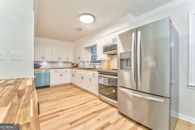 kitchen featuring light wood-style flooring, a sink, white cabinetry, stainless steel appliances, and wooden counters