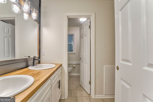 bathroom featuring a sink, a textured ceiling, toilet, and tile patterned flooring