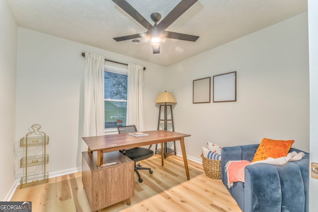 office area with baseboards, a textured ceiling, light wood-type flooring, and a ceiling fan