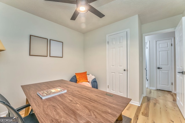 office area featuring baseboards, light wood-style flooring, a textured ceiling, and a ceiling fan