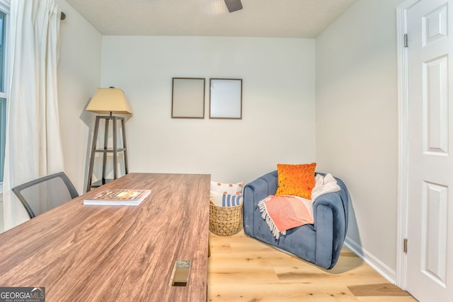 sitting room with baseboards, a textured ceiling, a ceiling fan, and wood finished floors