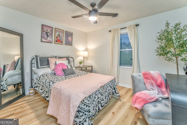 bedroom with a textured ceiling, ceiling fan, and wood finished floors