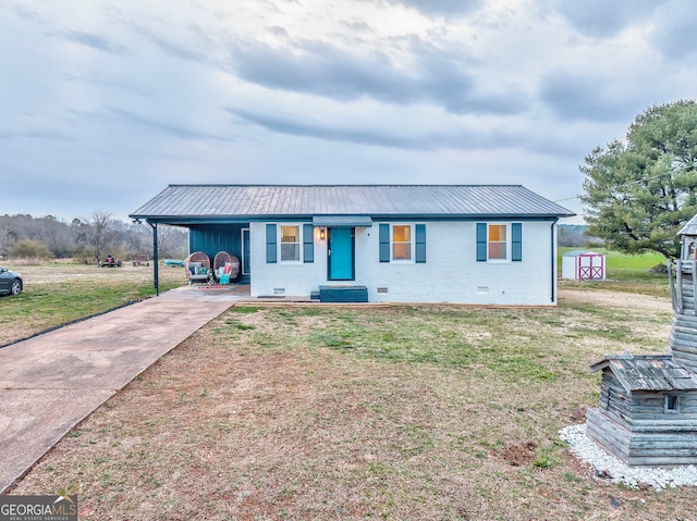 view of front of home with a storage shed, a carport, a front yard, and crawl space